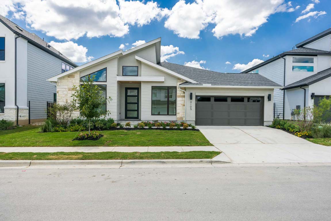 9105 Flatbush Road Austin, TX 78744 - Photo 1 of 1 View of front of home with stone siding, driveway, roof with shingles, and a front yard