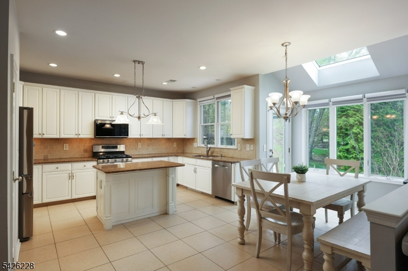 5 Gordon Place Bernards, NJ 07920 - Photo 8 of 30 a kitchen with stainless steel appliances granite countertop a stove top oven a sink dishwasher a dining table and chairs with wooden floor