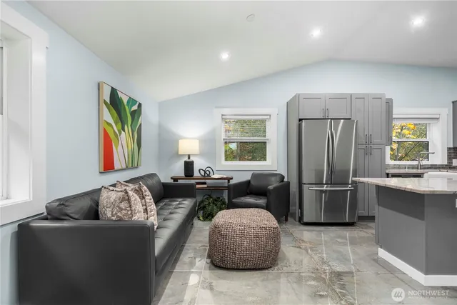 a living room with furniture a large window and stainless steel appliances