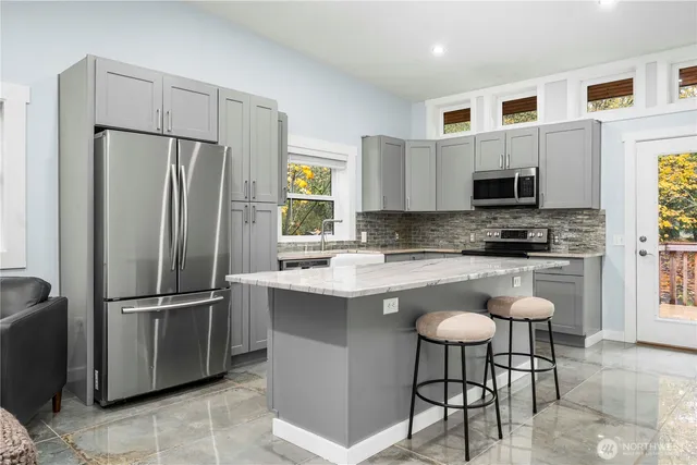 a kitchen with stainless steel appliances granite countertop a refrigerator a stove a sink a microwave a dining table and chairs