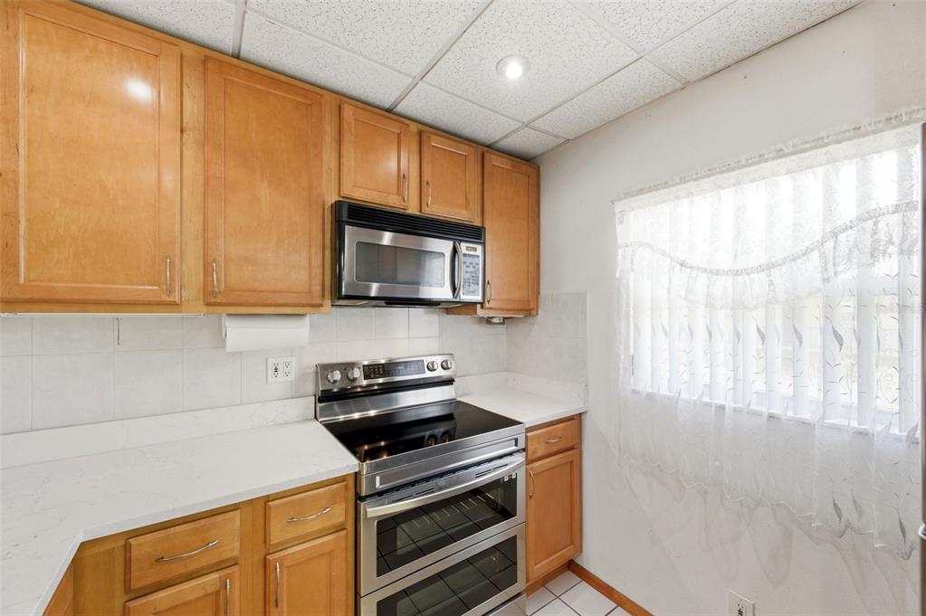 11485 Oakhurst Road, Unit 200208 Largo, FL 33774 - Photo 14 of 25 a kitchen with stainless steel appliances a stove a microwave and white cabinets