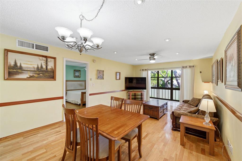 11485 Oakhurst Road, Unit 200208 Largo, FL 33774 - Photo 3 of 25 a view of a dining room with furniture a chandelier and wooden floor
