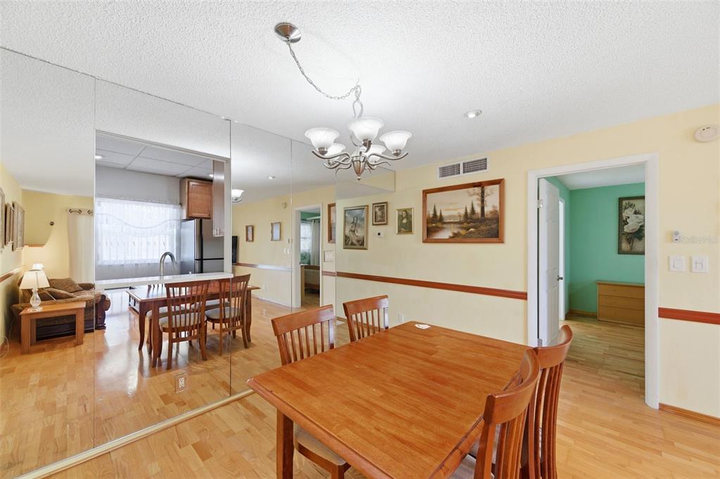 11485 Oakhurst Road, Unit 200208 Largo, FL 33774 - Photo 7 of 25 a dining room with wooden floor a chandelier a wooden table and chairs