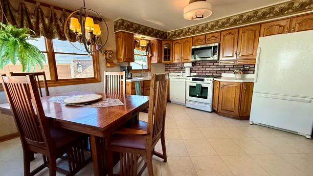 a kitchen with stainless steel appliances granite countertop a stove a refrigerator a dining table and chairs with wooden floor