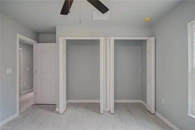 an empty room with ceiling fan and window