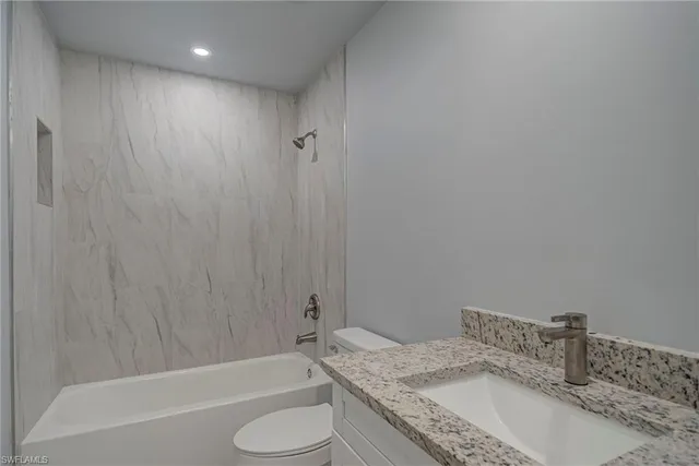 a bathroom with a granite countertop bathtub sink vanity toilet and shower