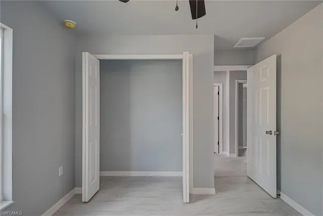 an empty room with chandelier fan and windows