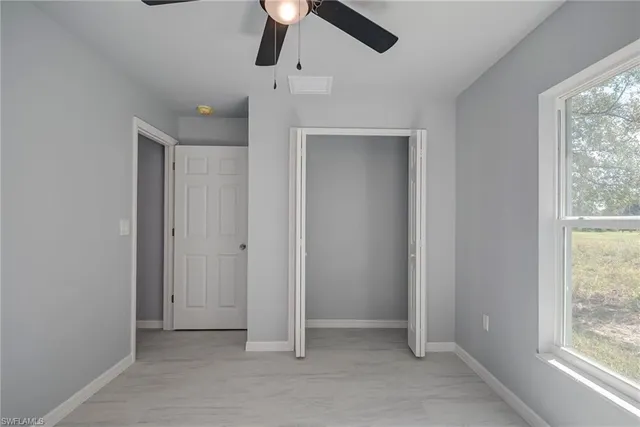 an empty room with a window and a fan