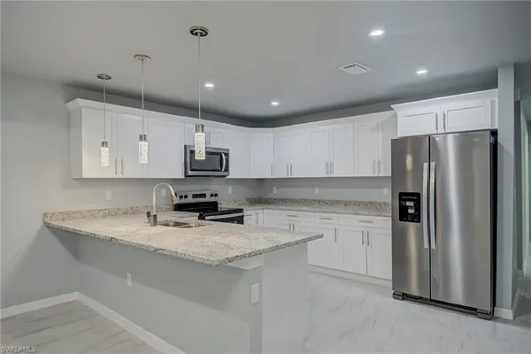 a kitchen with kitchen island granite countertop stainless steel appliances and refrigerator