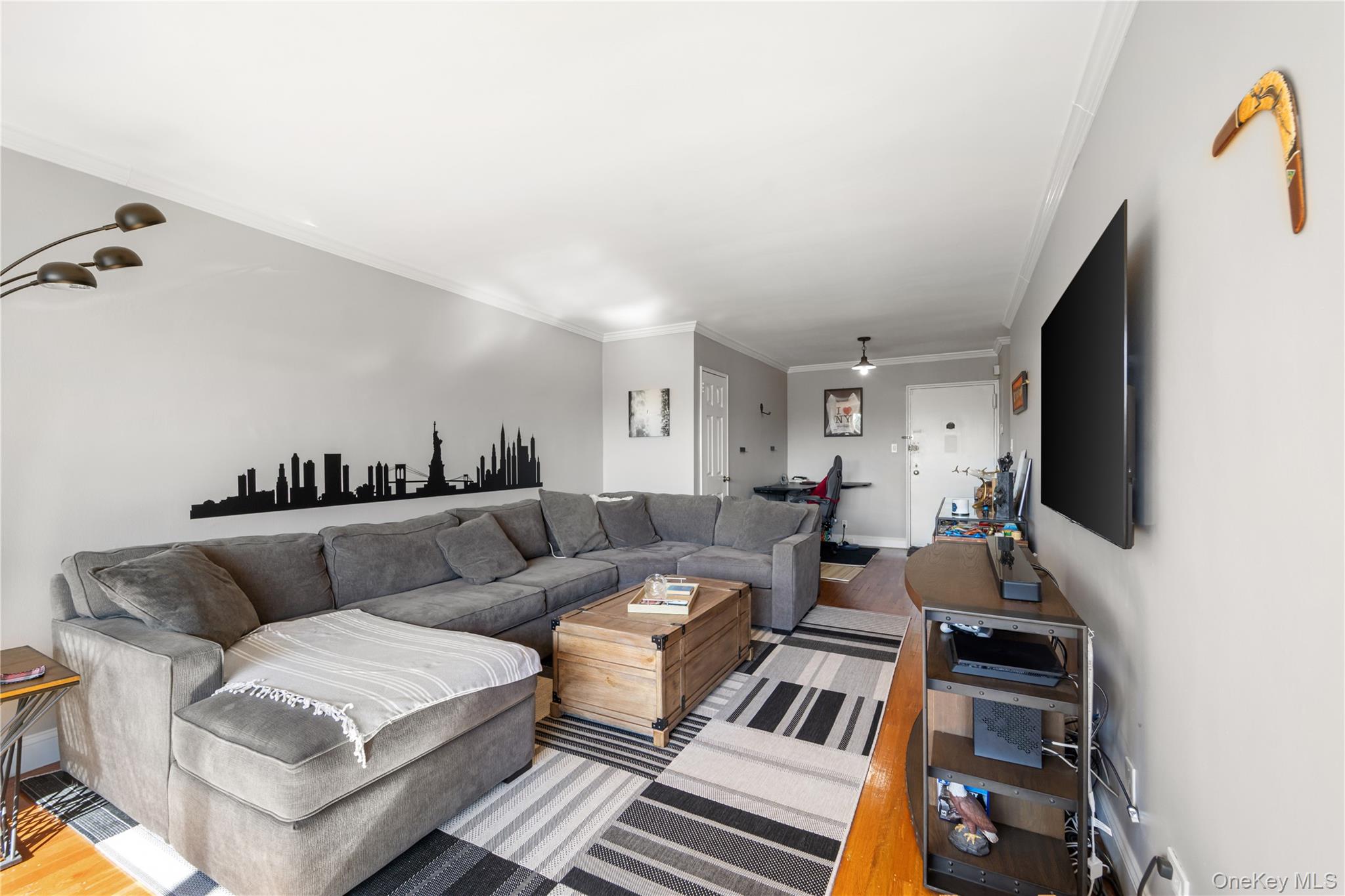 211-40 18th Avenue, Unit 6J Queens, NY 11360 - Photo 2 of 26 a living room with furniture a flat screen tv and a fireplace