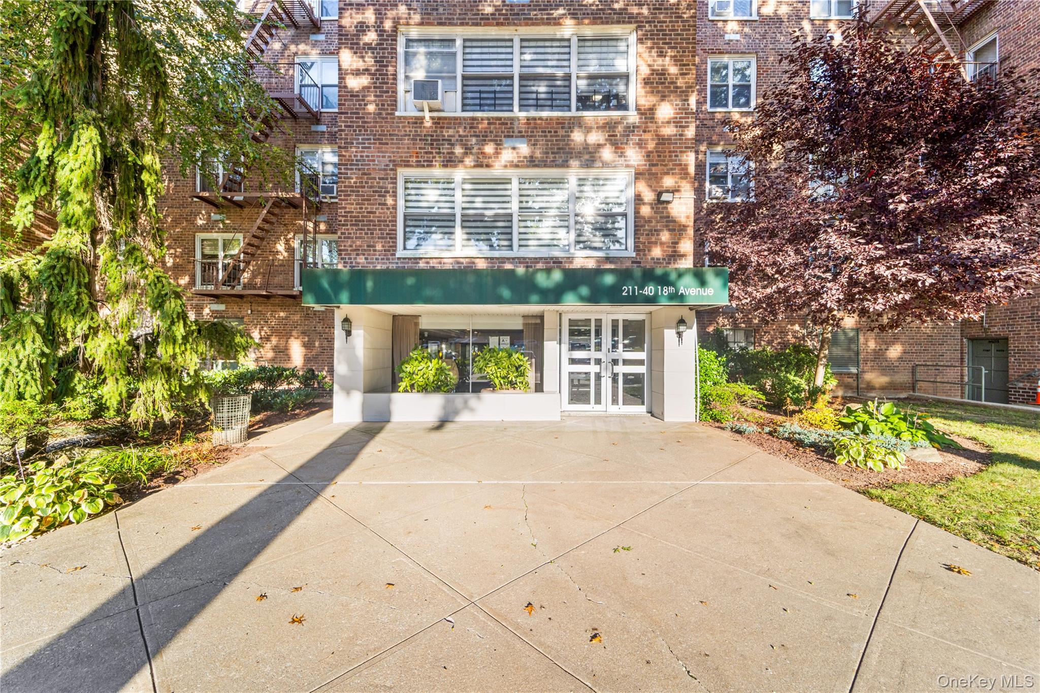 211-40 18th Avenue, Unit 6J Queens, NY 11360 - Photo 24 of 26 a front view of a building with a garden
