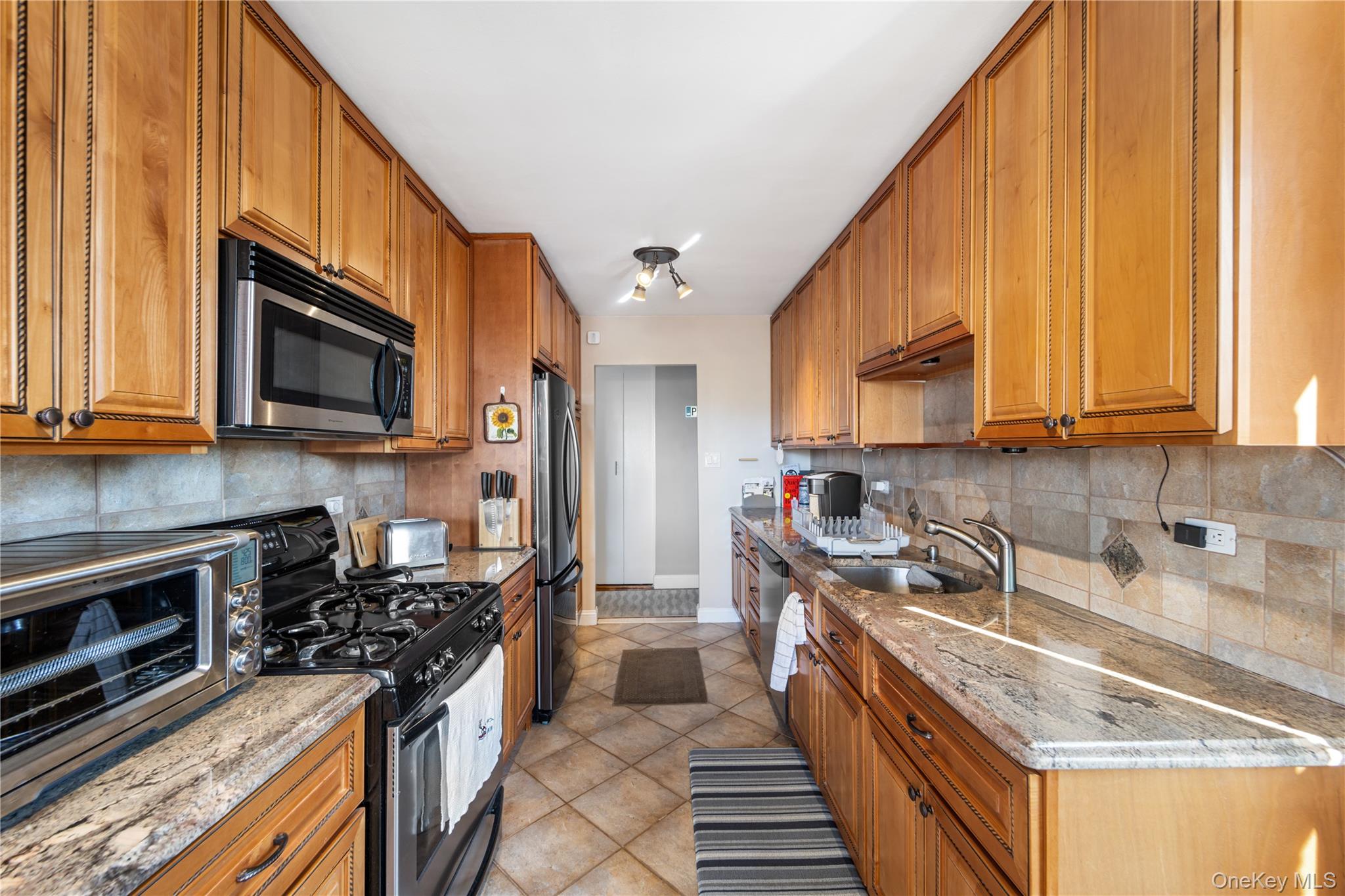 211-40 18th Avenue, Unit 6J Queens, NY 11360 - Photo 5 of 26 a kitchen with stainless steel appliances granite countertop a stove a sink and a microwave