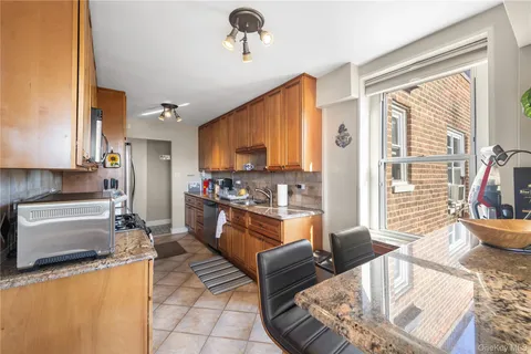 a kitchen with stainless steel appliances granite countertop a refrigerator a stove top oven and a sink with couches