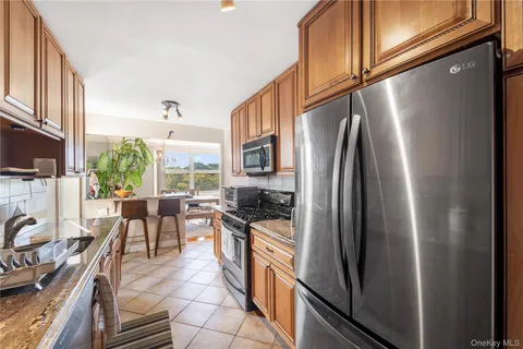 a kitchen with stainless steel appliances granite countertop a refrigerator a stove top oven a sink and dining table with wooden floor