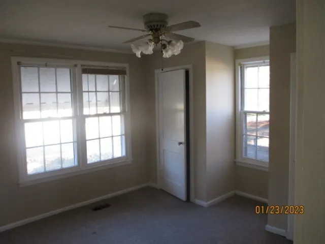an empty room with windows and fan