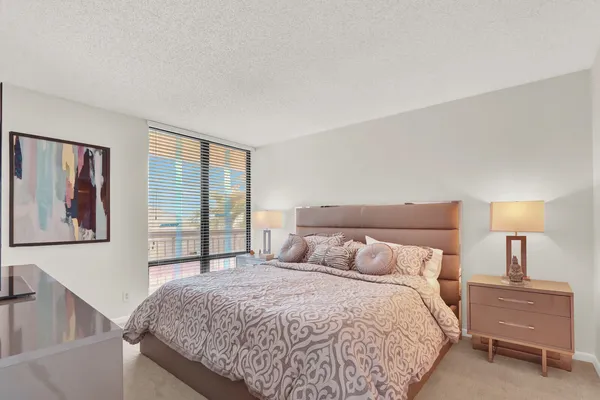 a bedroom with a large bed and a lamp on dresser