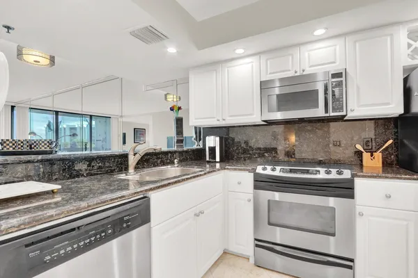 a kitchen with granite countertop white cabinets and white appliances