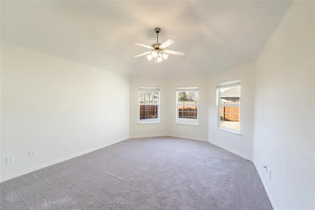 an empty room with windows and ceiling fan