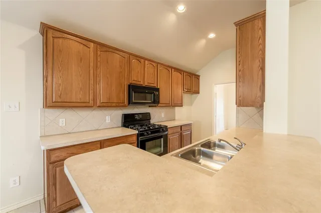 a kitchen with stainless steel appliances granite countertop a stove a sink and a microwave