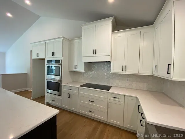 a kitchen with granite countertop white cabinets and refrigerator