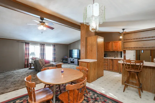 a dining room with wooden floor a chandelier a wooden table and chairs