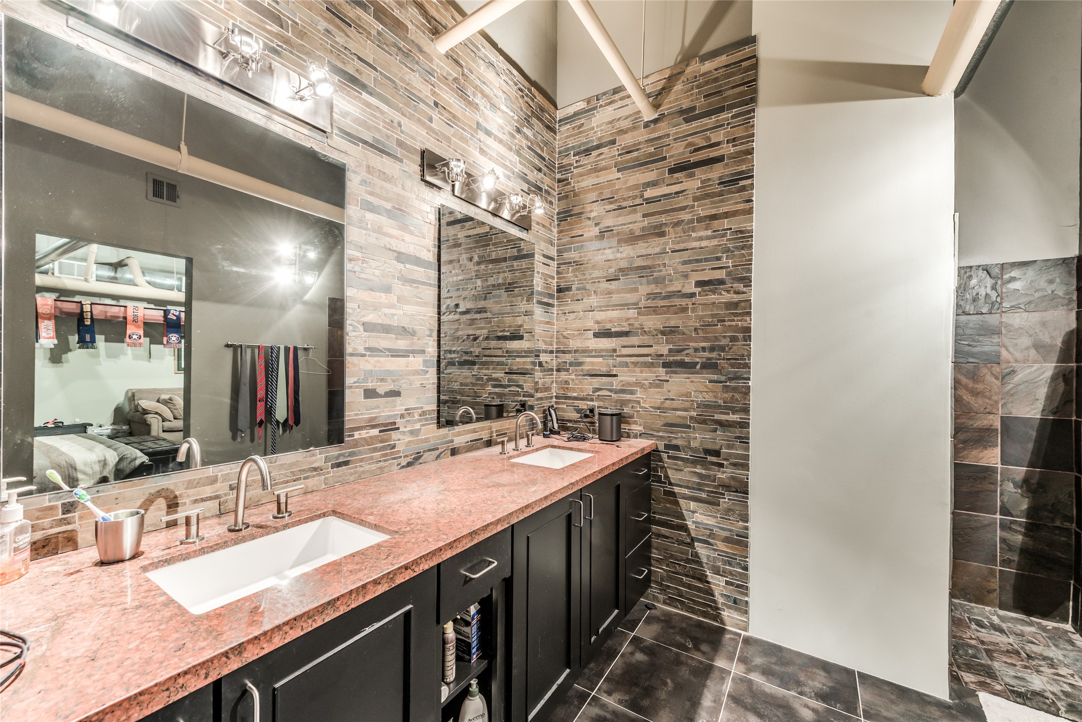 705 Main Street, Unit 215 Houston, TX 77002 - Photo 25 of 36 This modern bathroom features a dual-sink vanity with sleek granite countertops and dark cabinetry.