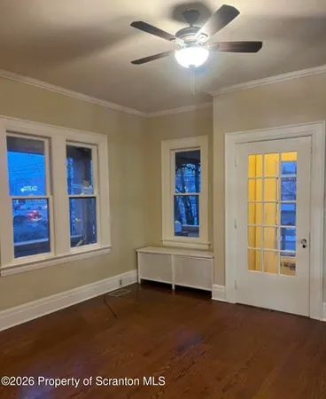 a view of an empty room with wooden floor and a window