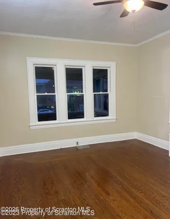 an empty room with wooden floor fan and windows
