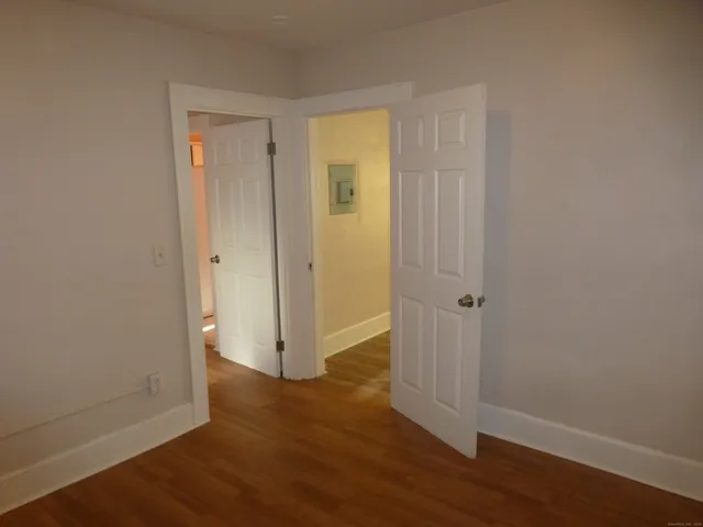 a view of an empty room with a window and wooden floor