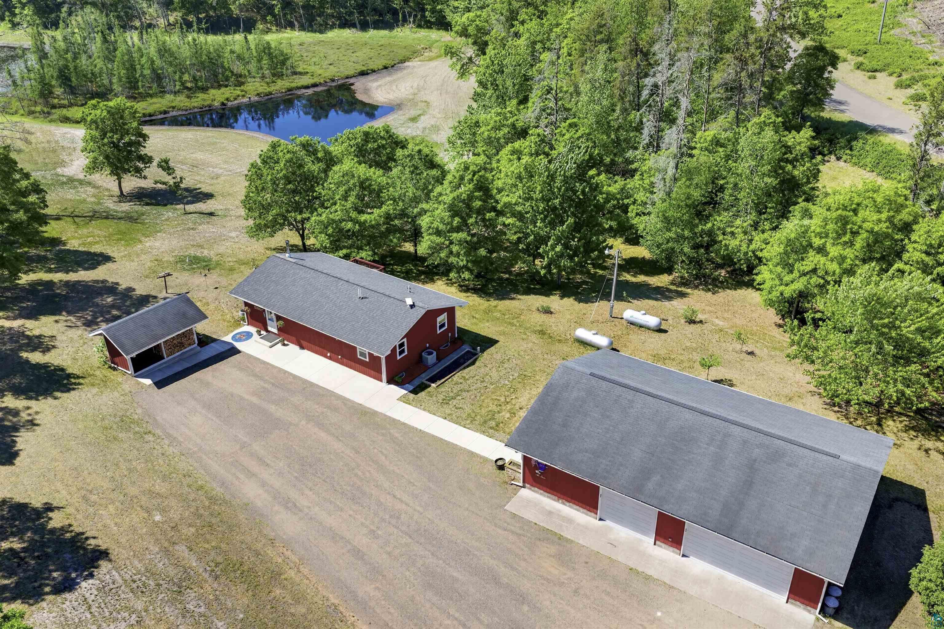 11702 East Mail Road Gordon, WI 54838 - Photo 14 of 60 Red residence with a dark gray shingle roof, accompanied by a detached shed and a large outbuilding