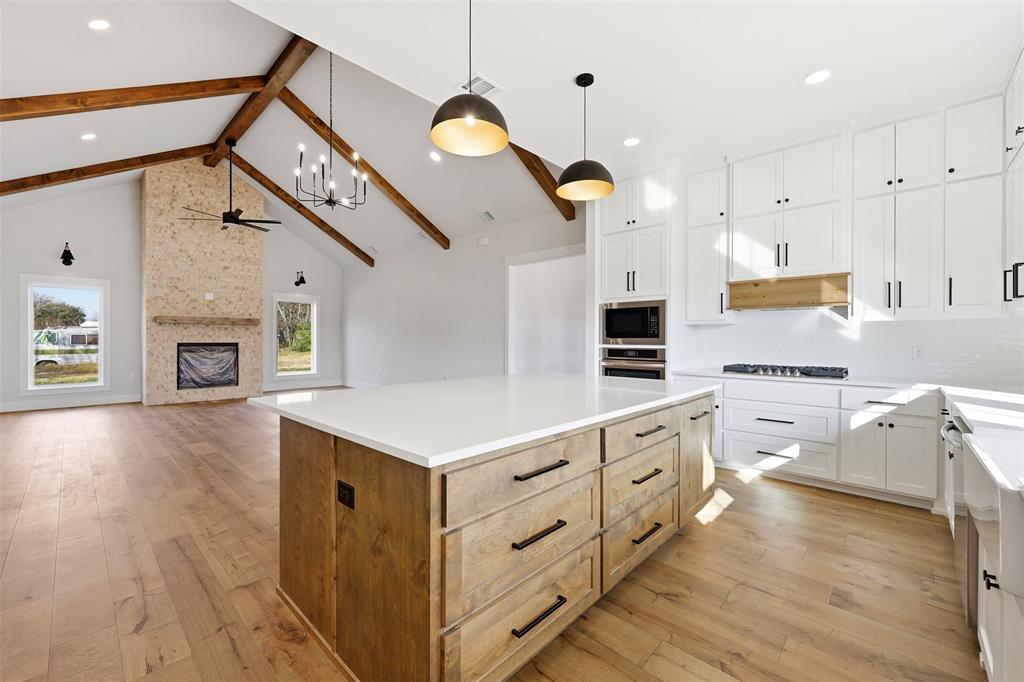 509 Emma Lane Grandview, TX 76050 - Photo 13 of 36 a kitchen with cabinets wooden floor and a fireplace