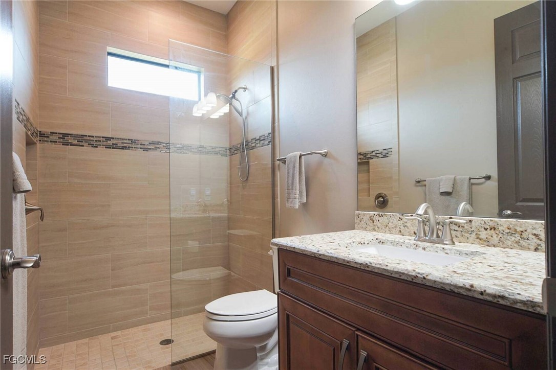 6142 Calusa Rdg Trail Bokeelia, FL 33922 - Photo 18 of 43 a bathroom with a granite countertop sink a toilet and shower