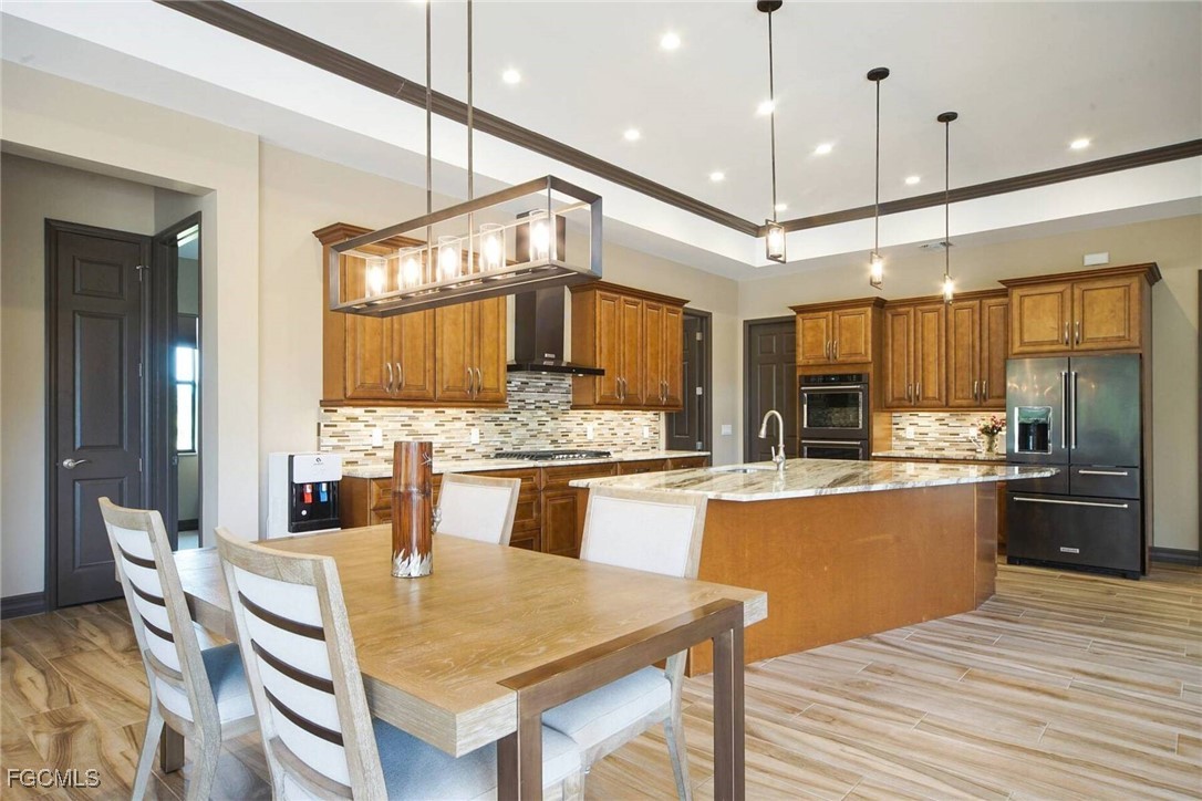 6142 Calusa Rdg Trail Bokeelia, FL 33922 - Photo 6 of 43 a kitchen with stainless steel appliances kitchen island granite countertop a table chairs and a wooden floor