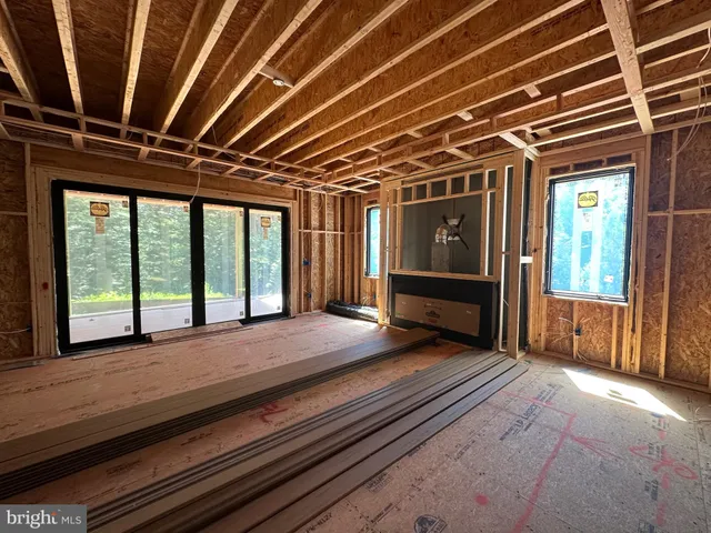 a view of an empty room with wooden floor and windows