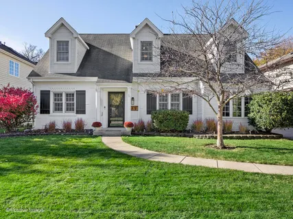 a house that is sitting in front of a big yard with potted plants