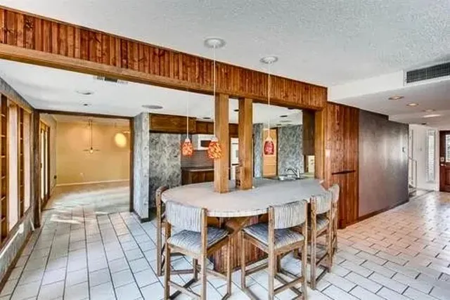 a dining hall with stainless steel appliances kitchen island a table and chairs in it
