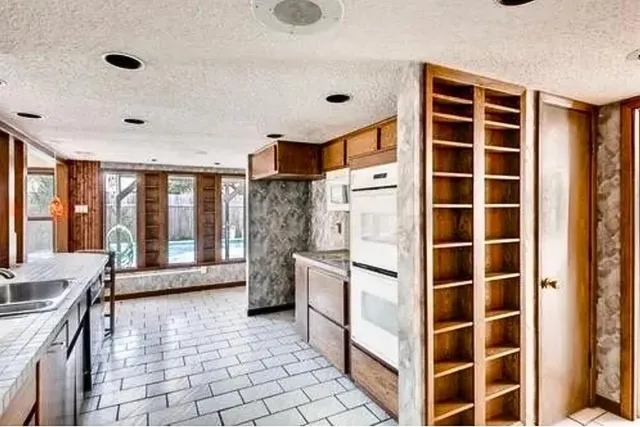 a large white kitchen with granite countertop a sink and a refrigerator