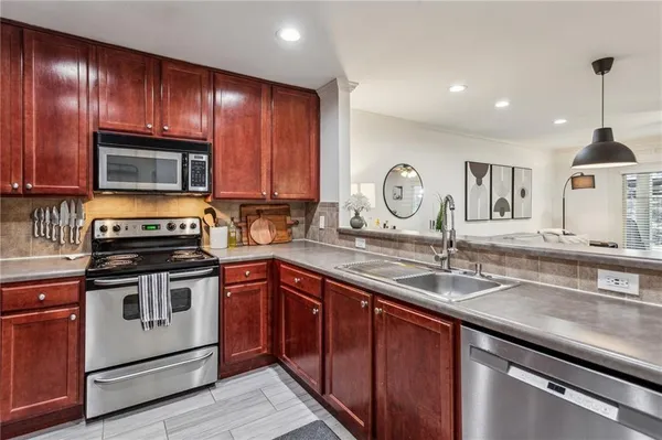 a kitchen with granite countertop wooden cabinets stainless steel appliances and a sink