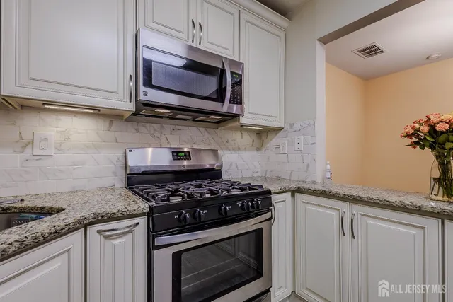 a kitchen with granite countertop stainless steel appliances a stove a microwave and cabinets