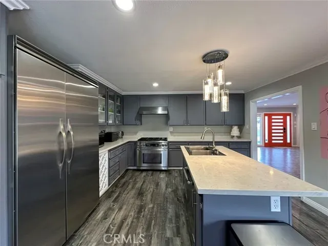 a kitchen with a refrigerator a sink dishwasher a oven and a dining table with wooden floor