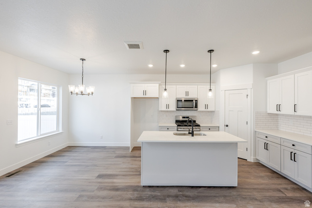 4775 Olive Avenue, Unit 412 Mapleton, UT 84664 - Photo 4 of 19 Kitchen with a kitchen island with sink, white cabinets, stainless steel appliances, suspended lighting, and light wood-style floors