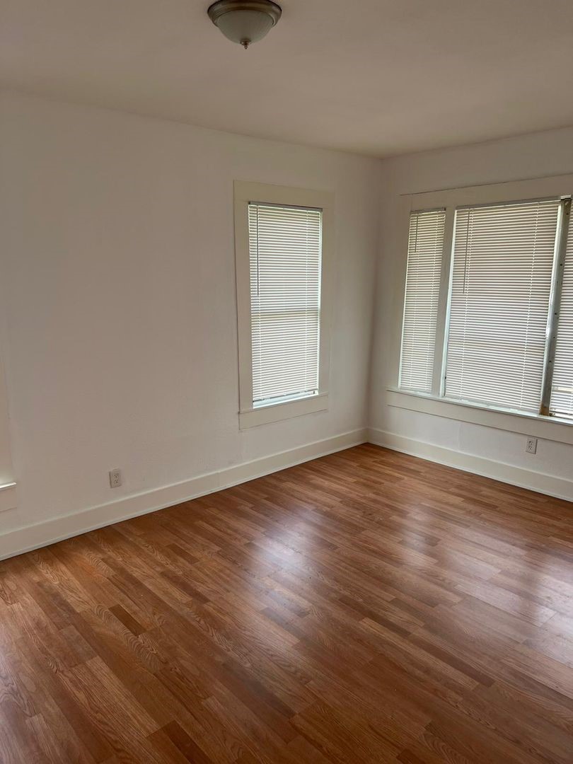 1030 Sherman Street Beaumont, TX 77701 - Photo 11 of 12 an empty room with wooden floor and windows