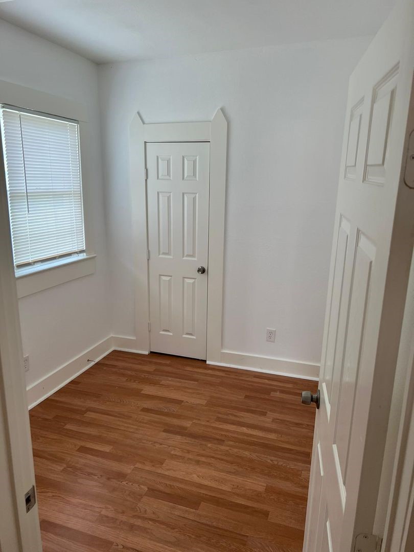 1030 Sherman Street Beaumont, TX 77701 - Photo 4 of 12 a view of an empty room with wooden floor and a window