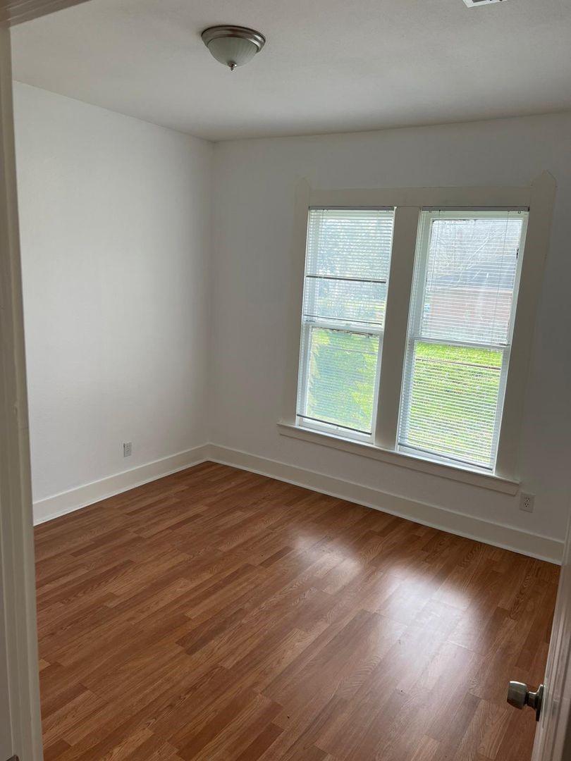1030 Sherman Street Beaumont, TX 77701 - Photo 7 of 12 an empty room with wooden floor and windows