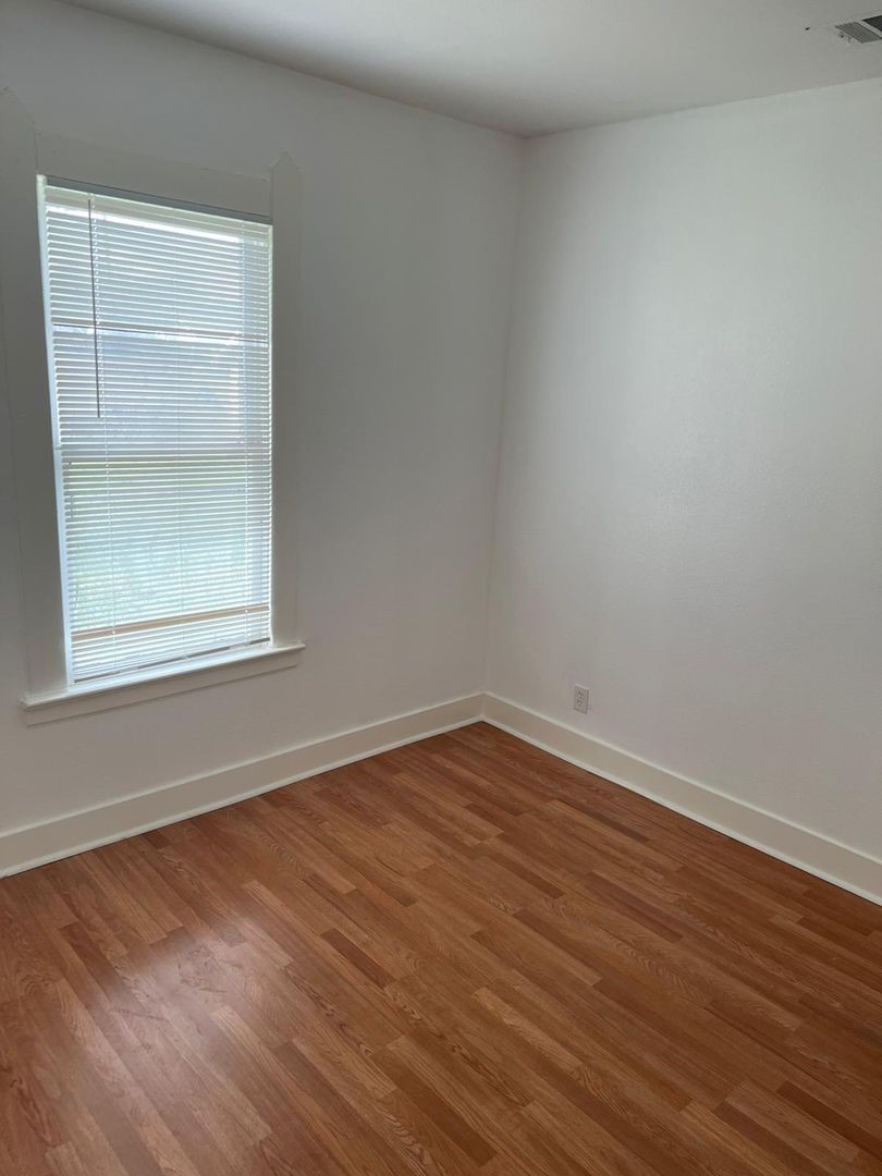1030 Sherman Street Beaumont, TX 77701 - Photo 8 of 12 a view of an empty room with wooden floor and a window