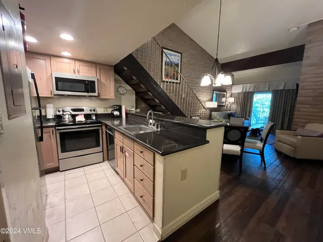 a kitchen with kitchen island granite countertop a sink a counter top space appliances and cabinets