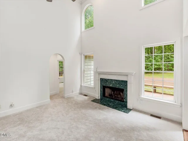 an empty room with windows and fireplace