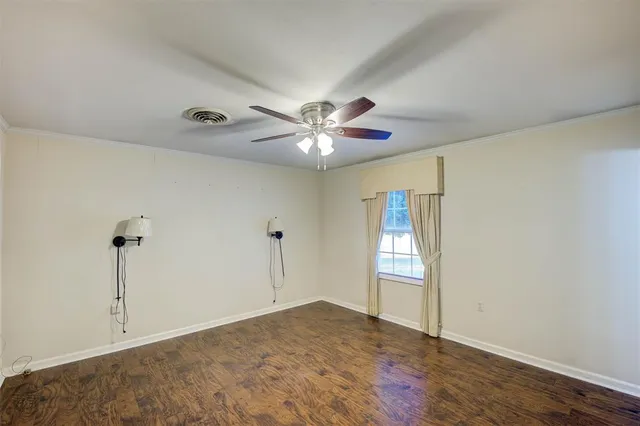 a view of an empty room with window and chandelier fan