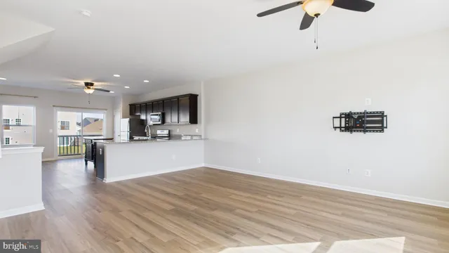 a view of kitchen and empty room with wooden floor