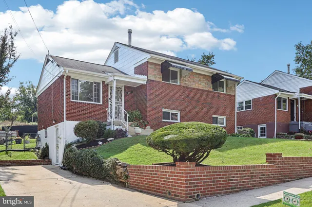 a brick house with a yard plants and big trees